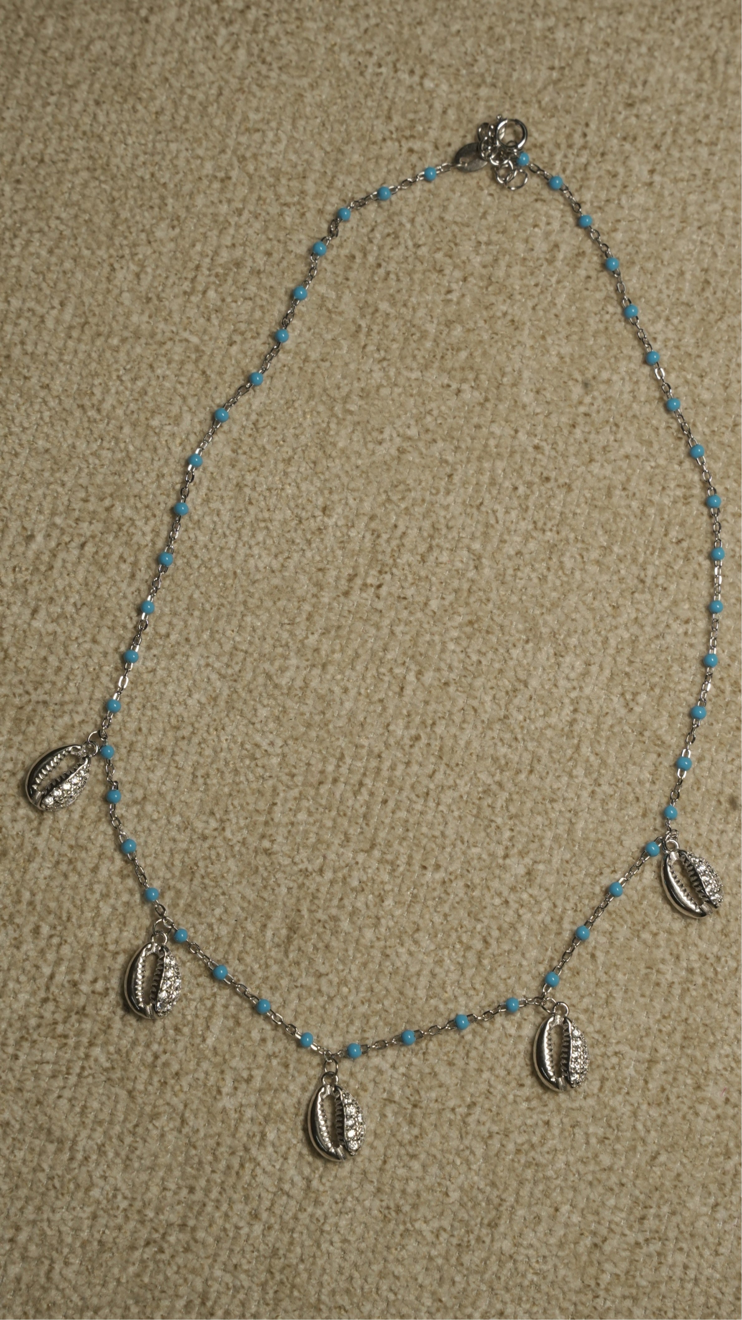 Full view of the beaded sterling silver chain with cubic zirconia-set shell charms spaced along the lower edge.