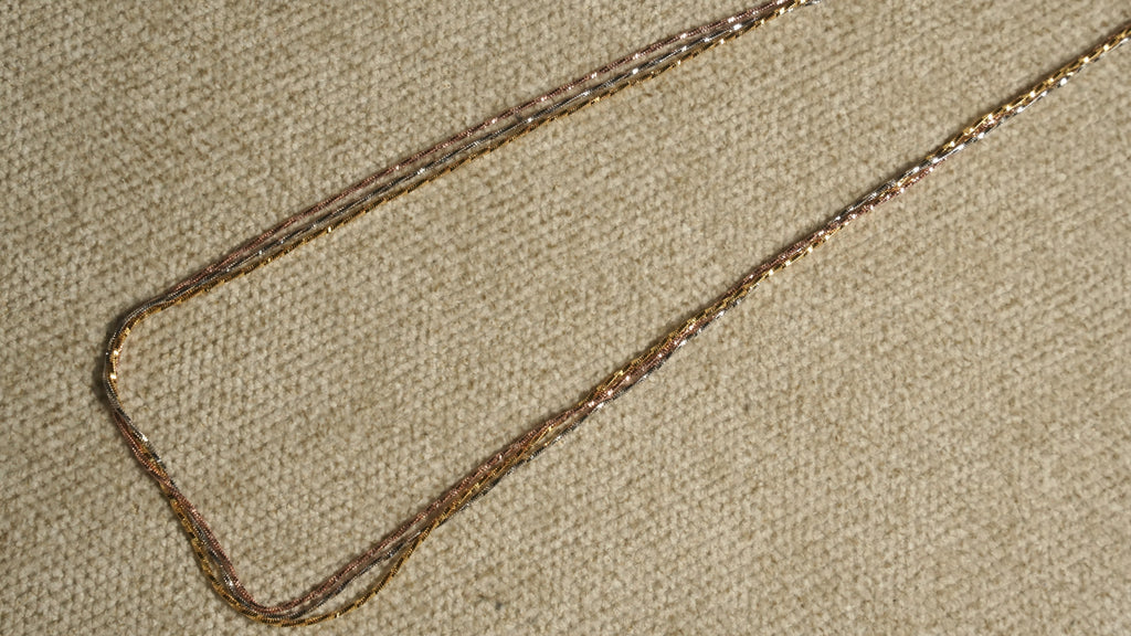 Close diagonal view of the tri-tone twisted chains running in parallel, their facet-cut texture catching the light.
