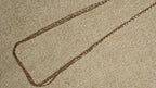 Close diagonal view of the tri-tone twisted chains running in parallel, their facet-cut texture catching the light.