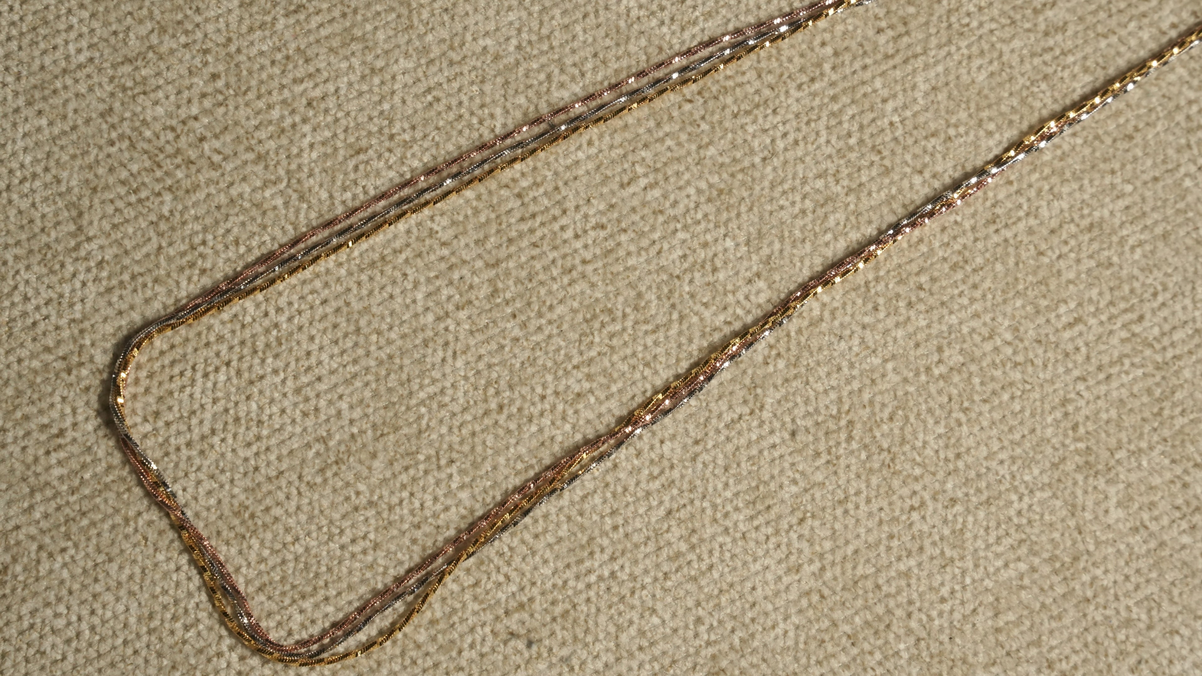 Close diagonal view of the tri-tone twisted chains running in parallel, their facet-cut texture catching the light.