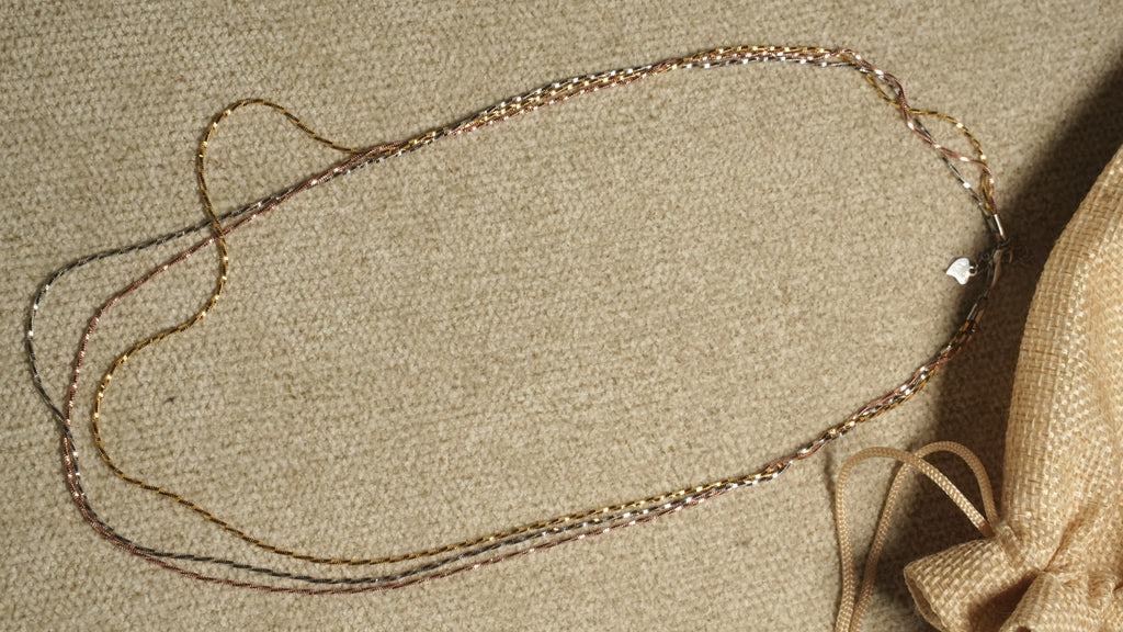 Close diagonal view of the tri-tone twisted chains running in parallel, their facet-cut texture catching the light.