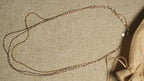 Close diagonal view of the tri-tone twisted chains running in parallel, their facet-cut texture catching the light.