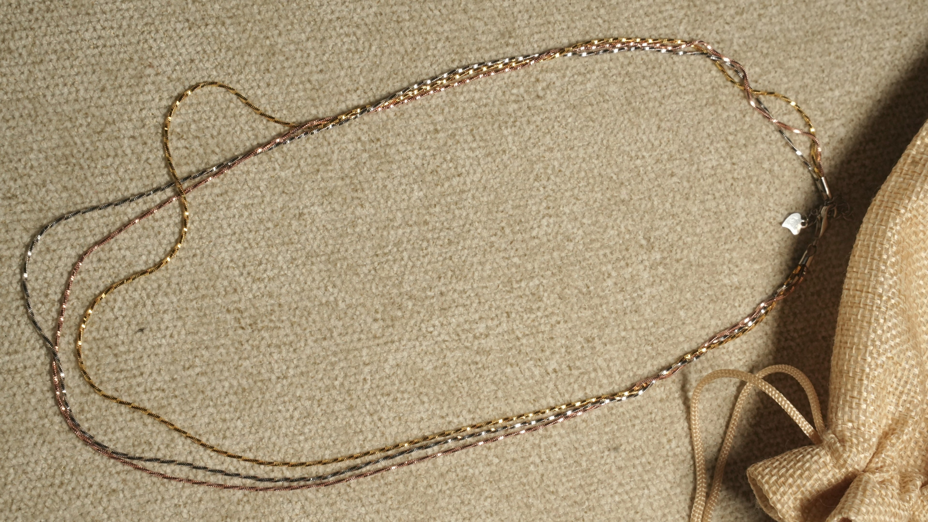 Close diagonal view of the tri-tone twisted chains running in parallel, their facet-cut texture catching the light.
