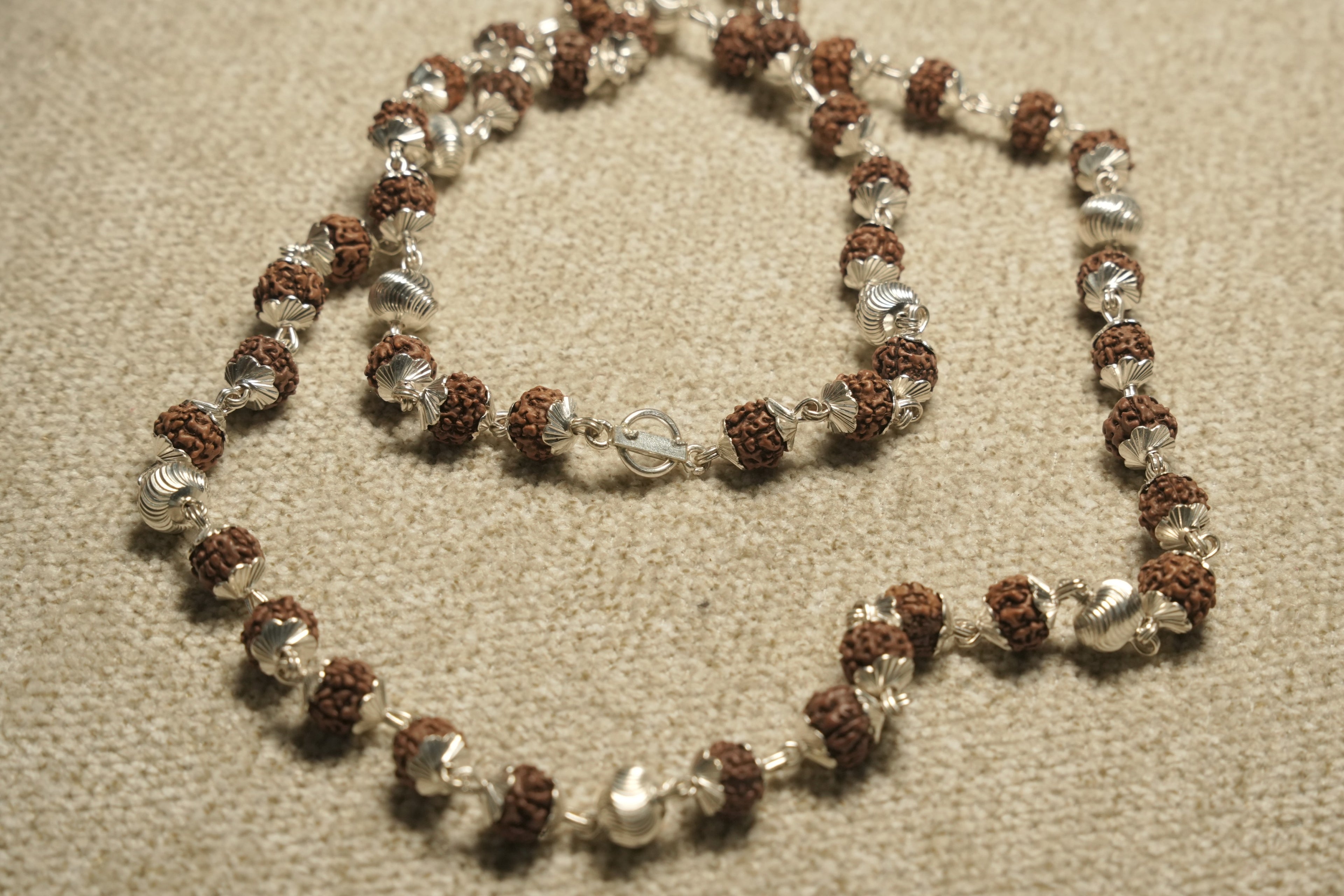Close view of the Rudraksha chain showing textured beads in fluted sterling silver caps and its bar closure.
