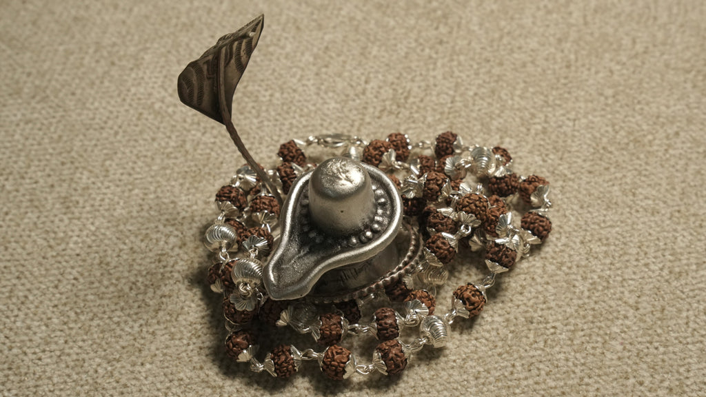 Rudraksha chain in sterling silver gathered around a small silver lingam ornament used as a styling prop.