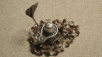 Rudraksha chain in sterling silver gathered around a small silver lingam ornament used as a styling prop.