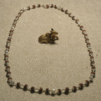 Full 65 cm Rudraksha chain laid open in an oval beside a small brass Nandi figurine.