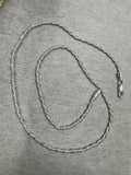 Full 50 cm length of the sterling silver Singapore chain necklace laid in loops on grey felt, with the lobster clasp at the right.