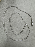Full 50 cm length of the sterling silver Singapore chain necklace laid in loops on grey felt, with the lobster clasp at the right.