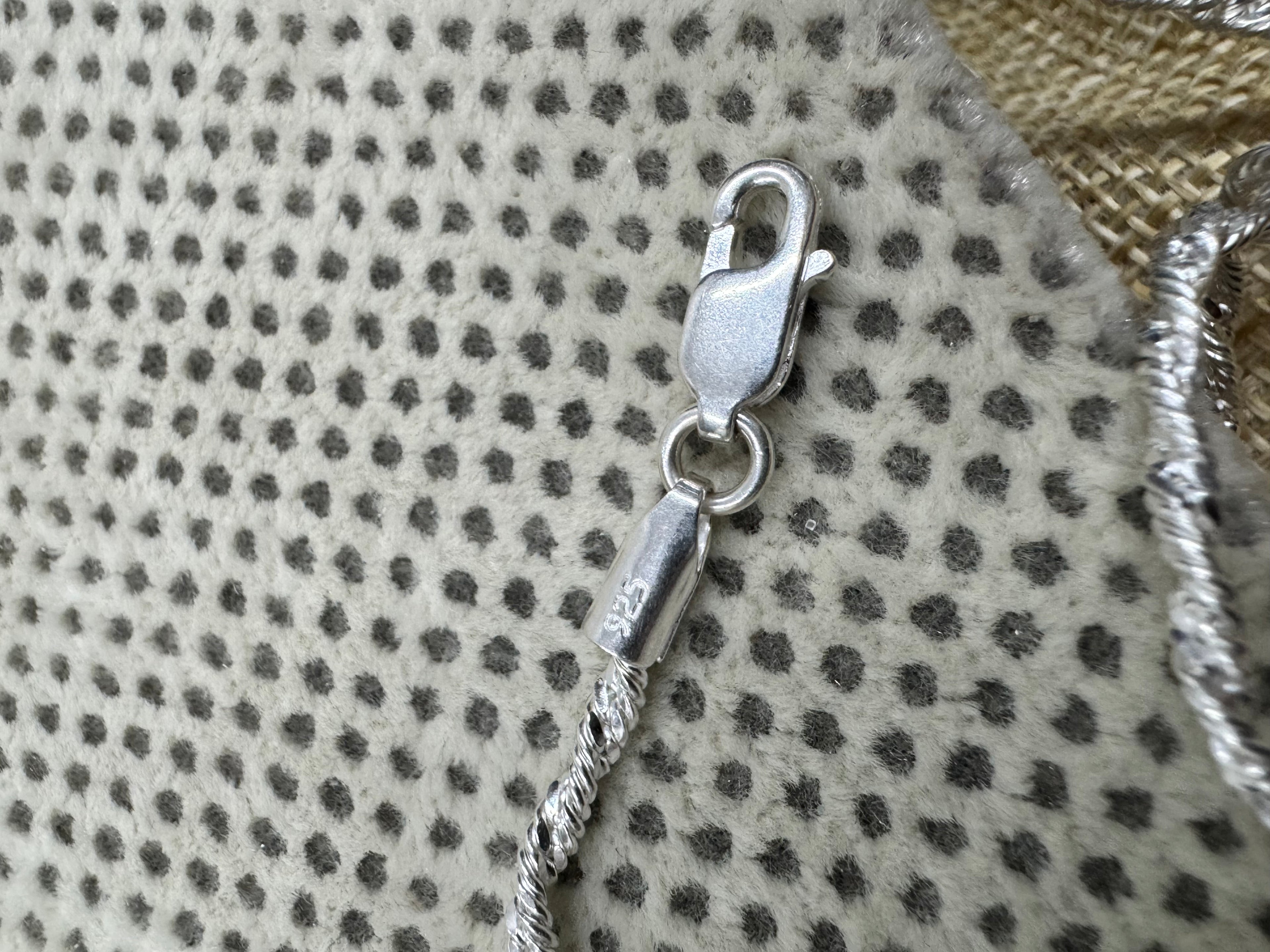 Close view of the lobster clasp and the stamped 925 end tag on the sterling silver chain necklace.