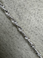 Single strand of the sterling silver Singapore chain photographed close on grey felt, showing the diamond-cut facets along the twist.