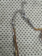 Lobster clasp and extender chain of the multi-strand sterling silver box chain necklace on spotted cream fabric.