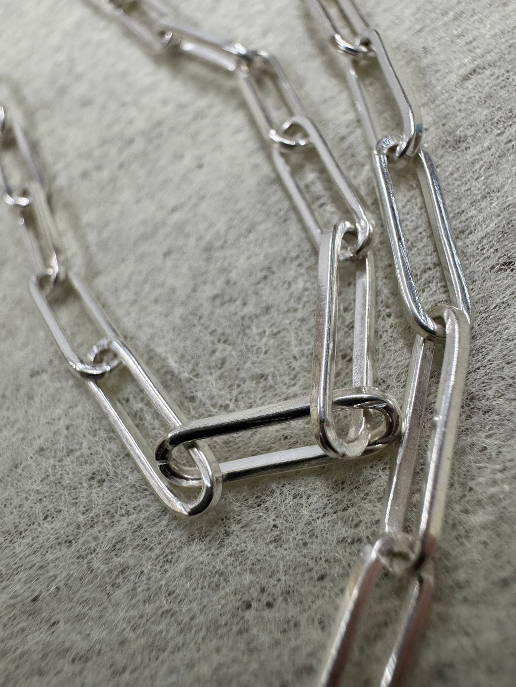 Macro view of the elongated flat links of the sterling silver paperclip chain necklace.