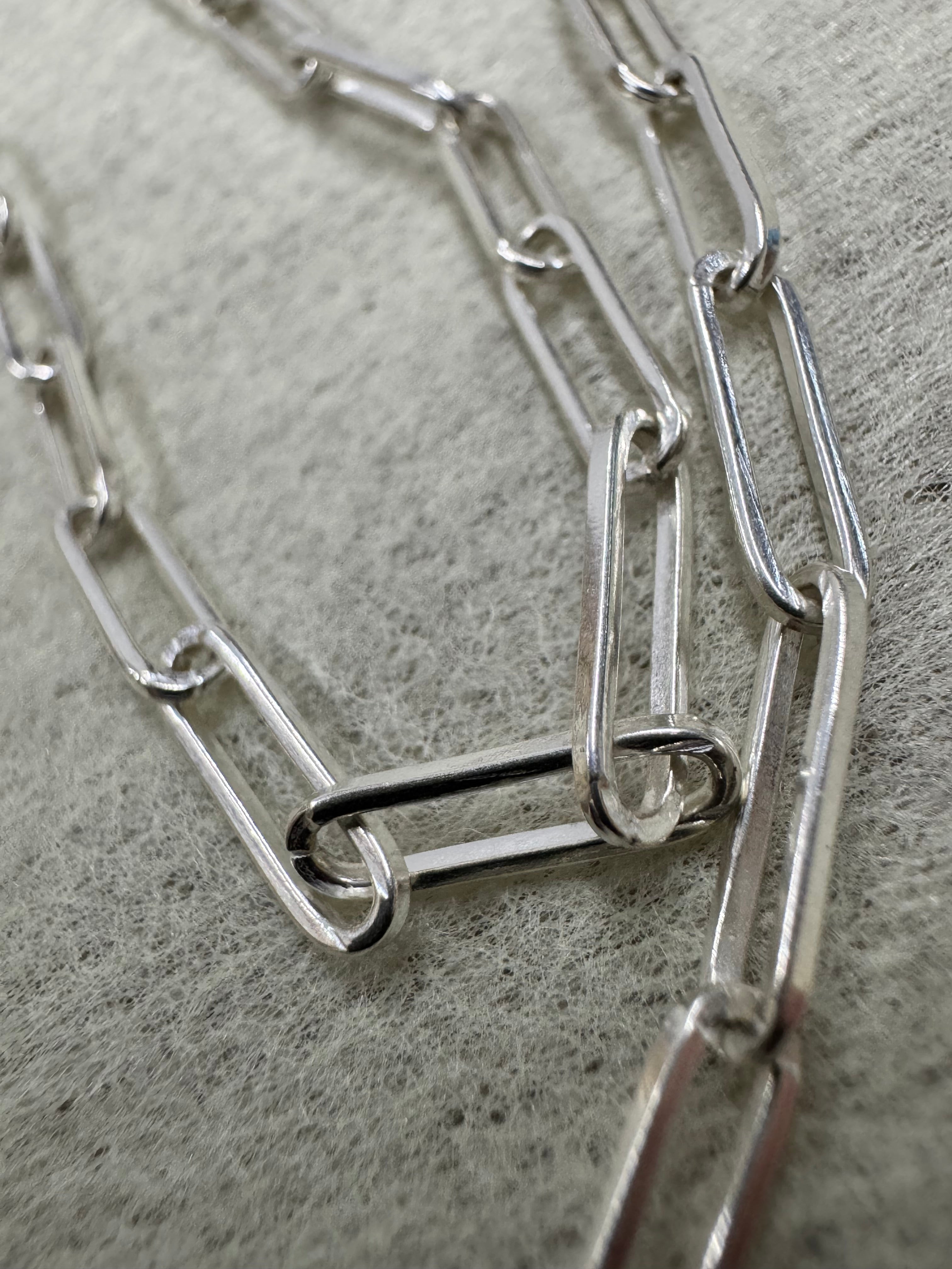 Macro view of the elongated flat links of the sterling silver paperclip chain necklace.