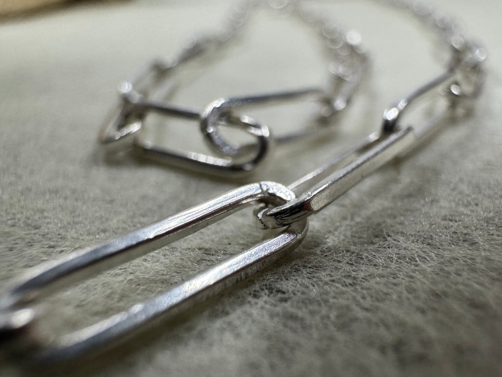 Close view of two joined links of the sterling silver paperclip chain necklace, showing the flattened sides.