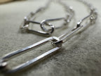 Close view of two joined links of the sterling silver paperclip chain necklace, showing the flattened sides.