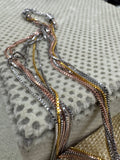 Strands of the sterling silver box chain necklace hanging from the end cap beside a jute pouch.