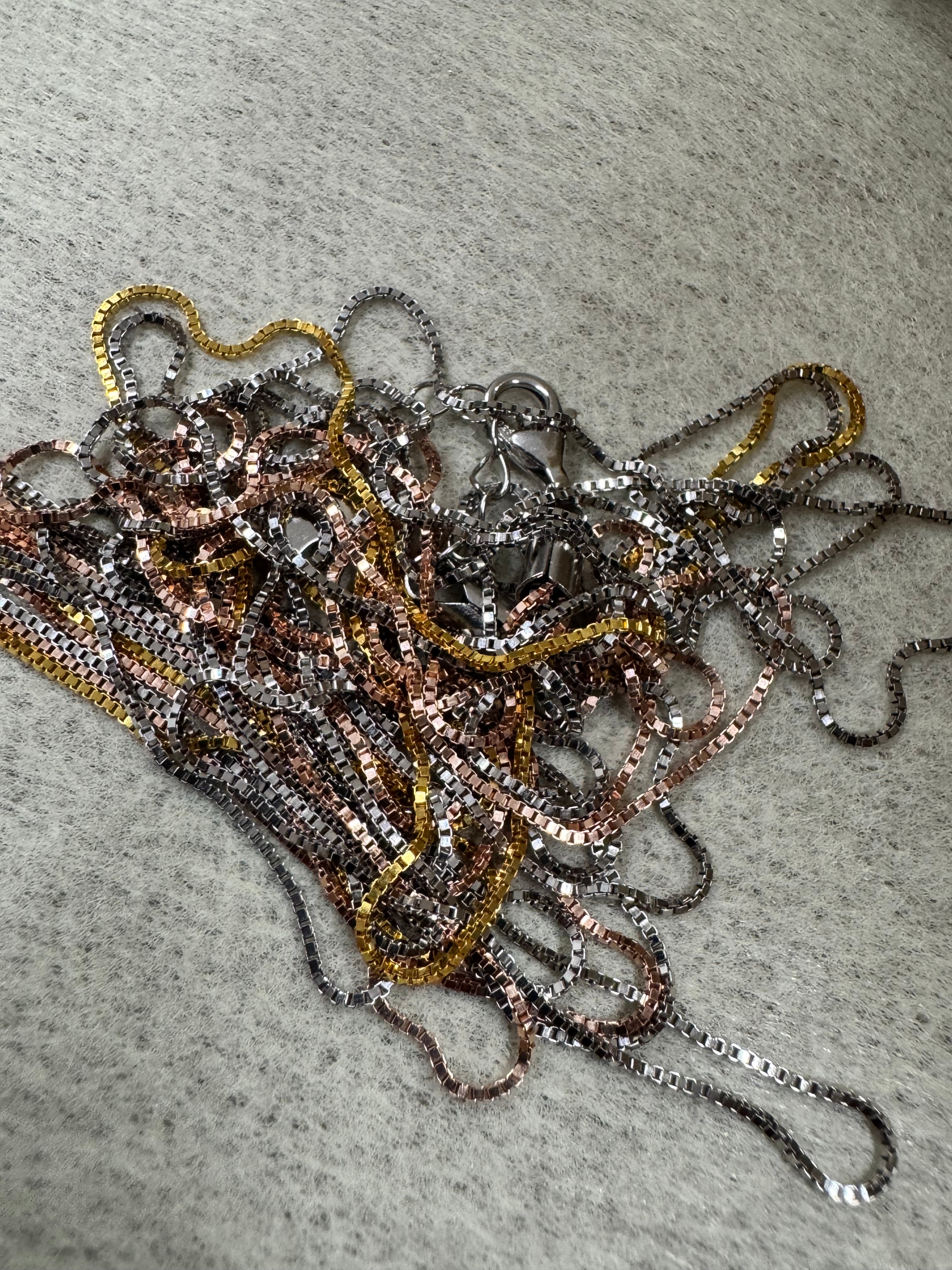Sterling silver multi-strand box chain necklace gathered loosely on grey felt.