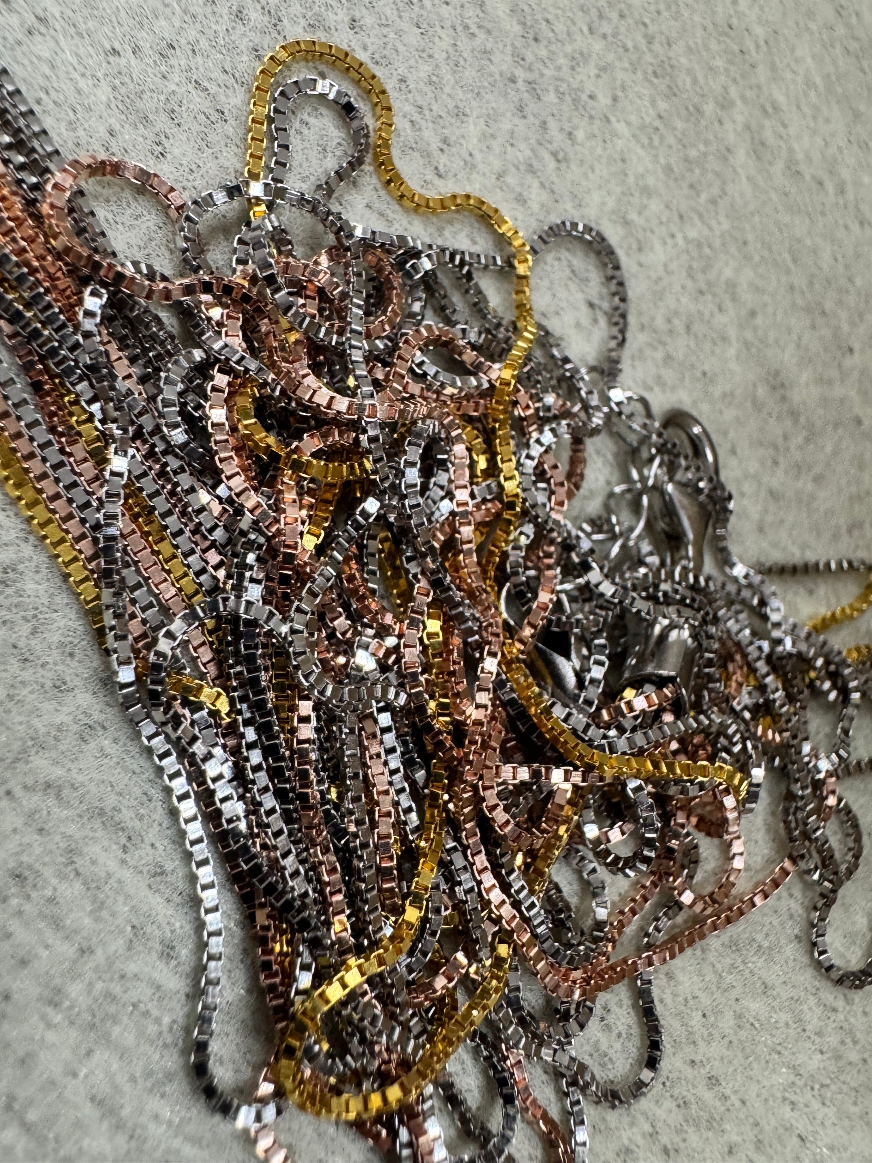 Sterling silver multi-strand box chain necklace gathered loosely on grey felt.