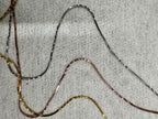 Separated strands of the sterling silver necklace, showing the diamond-cut facets running along each snake chain.