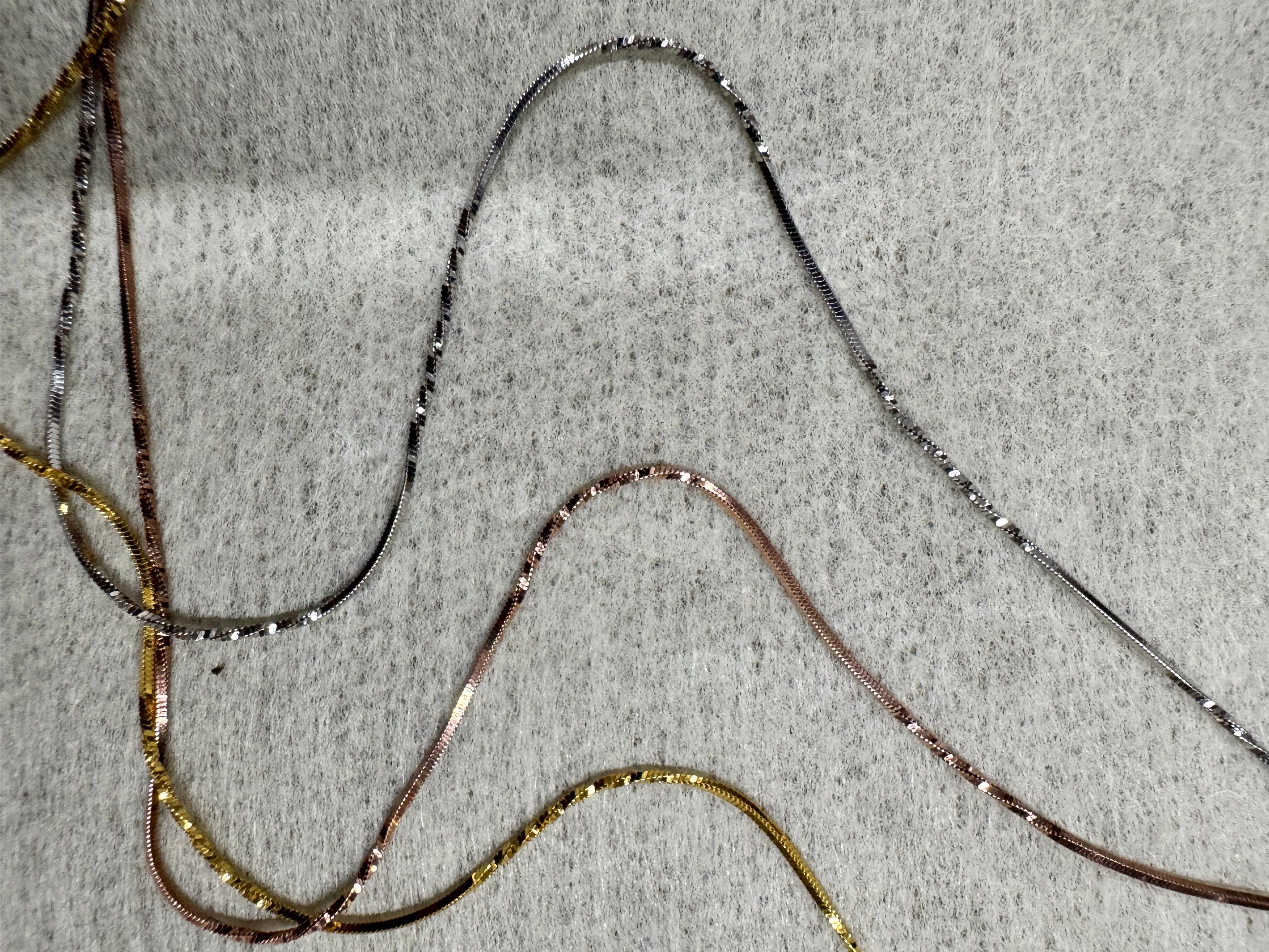 Separated strands of the sterling silver necklace, showing the diamond-cut facets running along each snake chain.