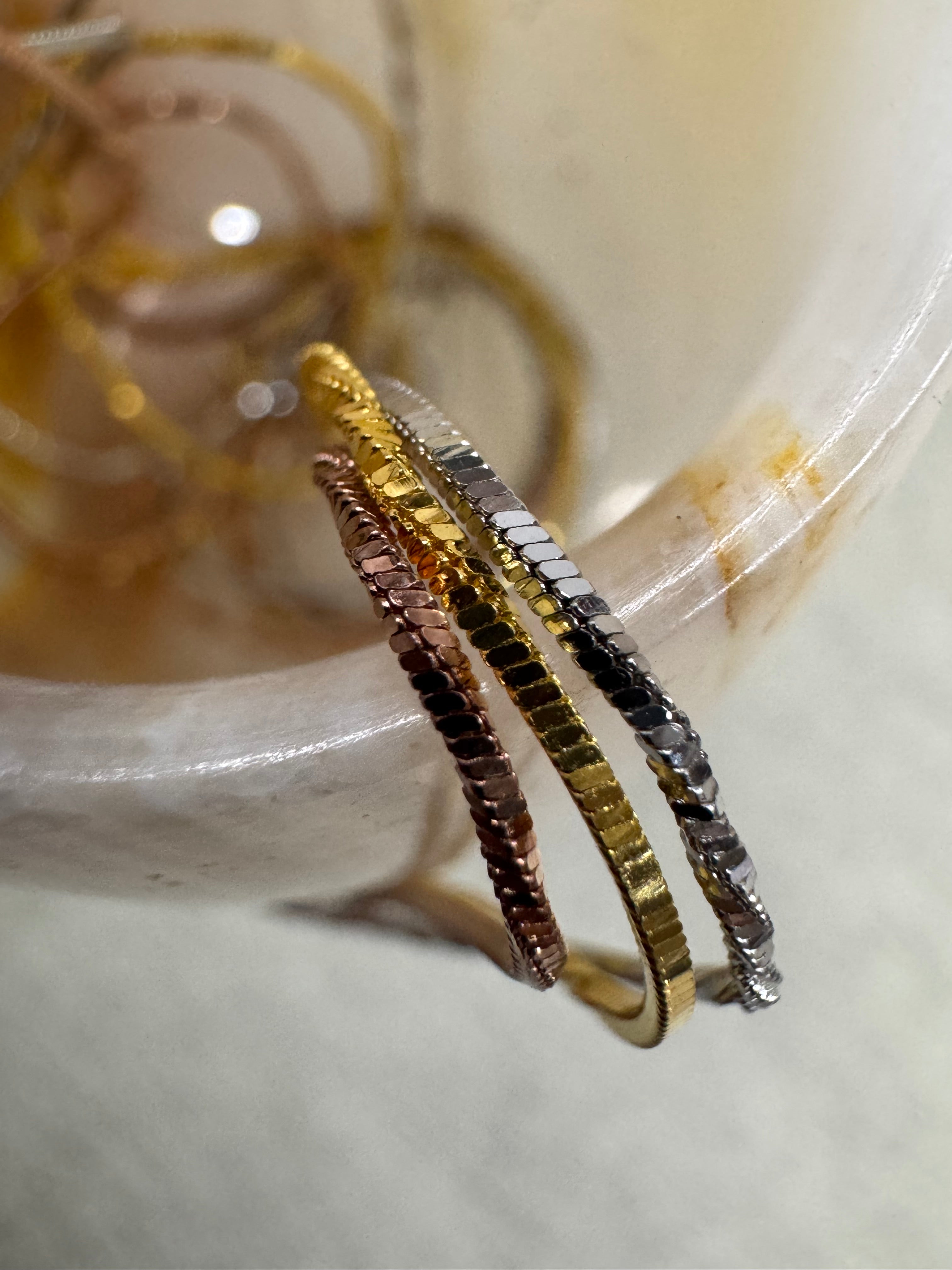 Close view of the sterling silver necklace's three snake chains in silver, gold-tone and rose-tone finishes.