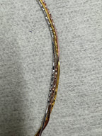 The three strands of the sterling silver snake chain necklace lying side by side in a shallow arc on grey felt.