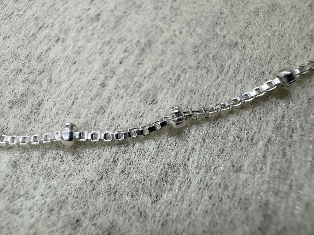 Close view of the square box links and two polished silver balls on the sterling silver necklace.