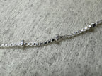 Close view of the square box links and two polished silver balls on the sterling silver necklace.