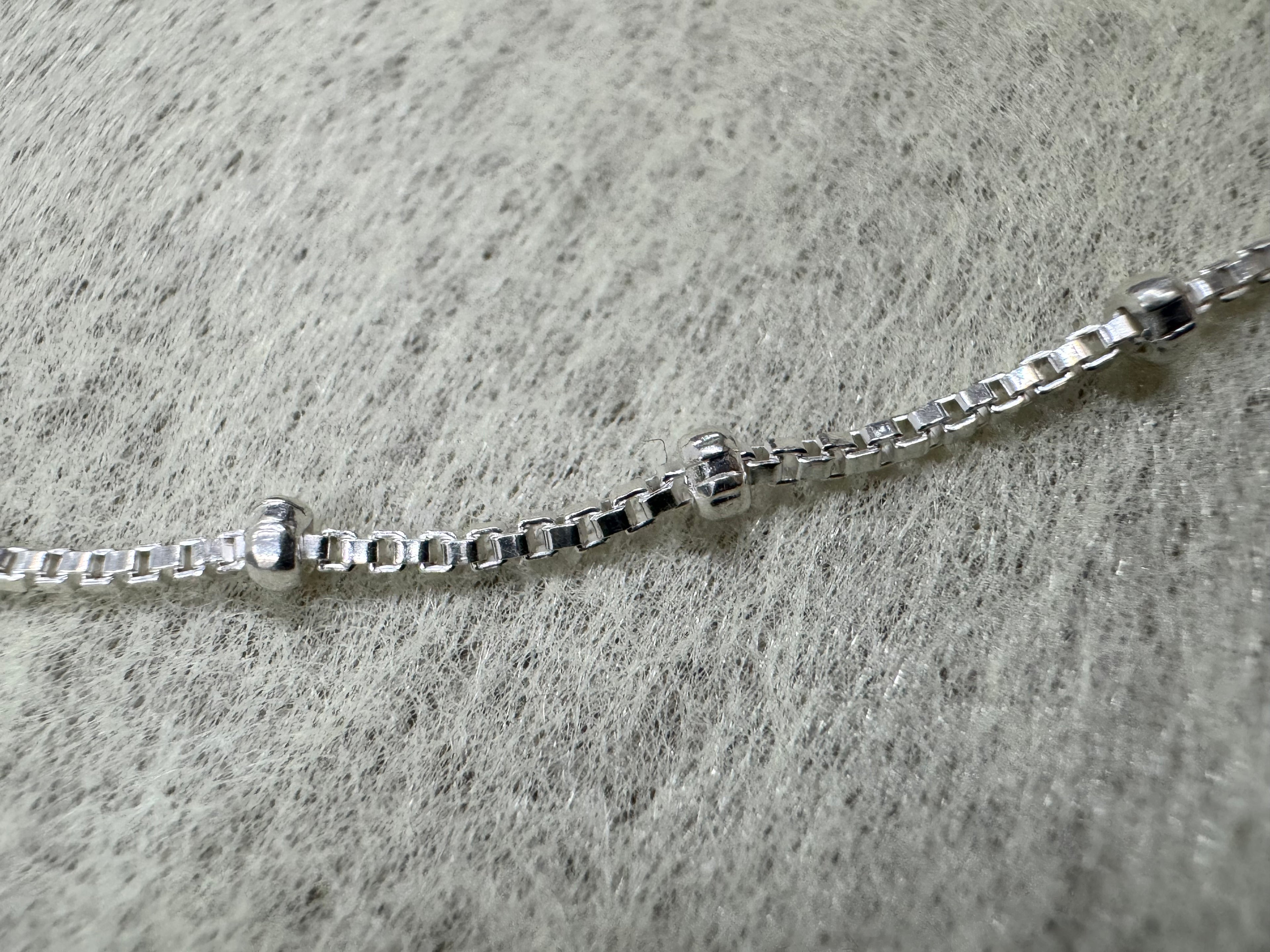 Close view of the square box links and two polished silver balls on the sterling silver necklace.