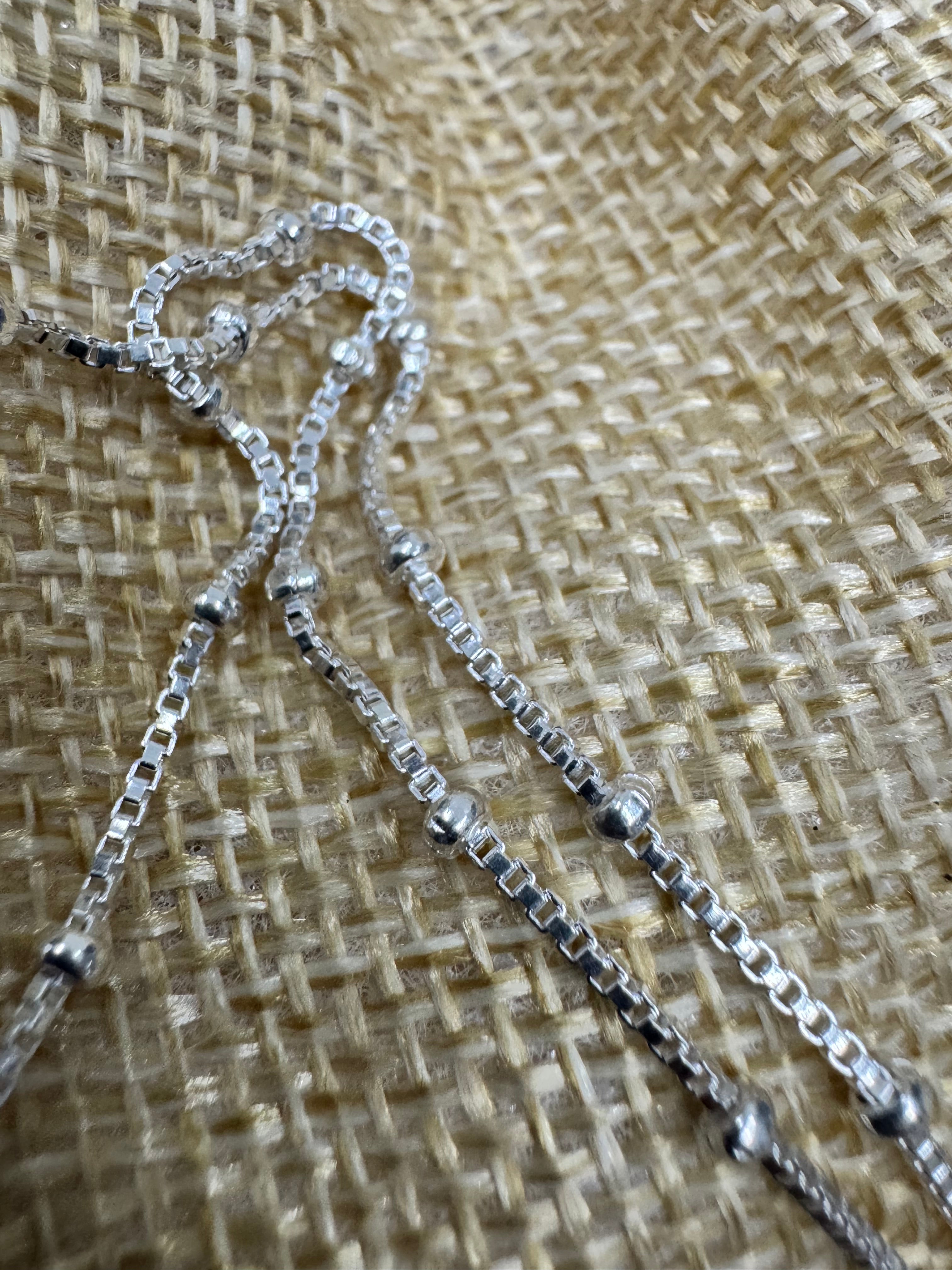 Sterling silver satellite box chain necklace on woven jute, the beaded stations catching light.