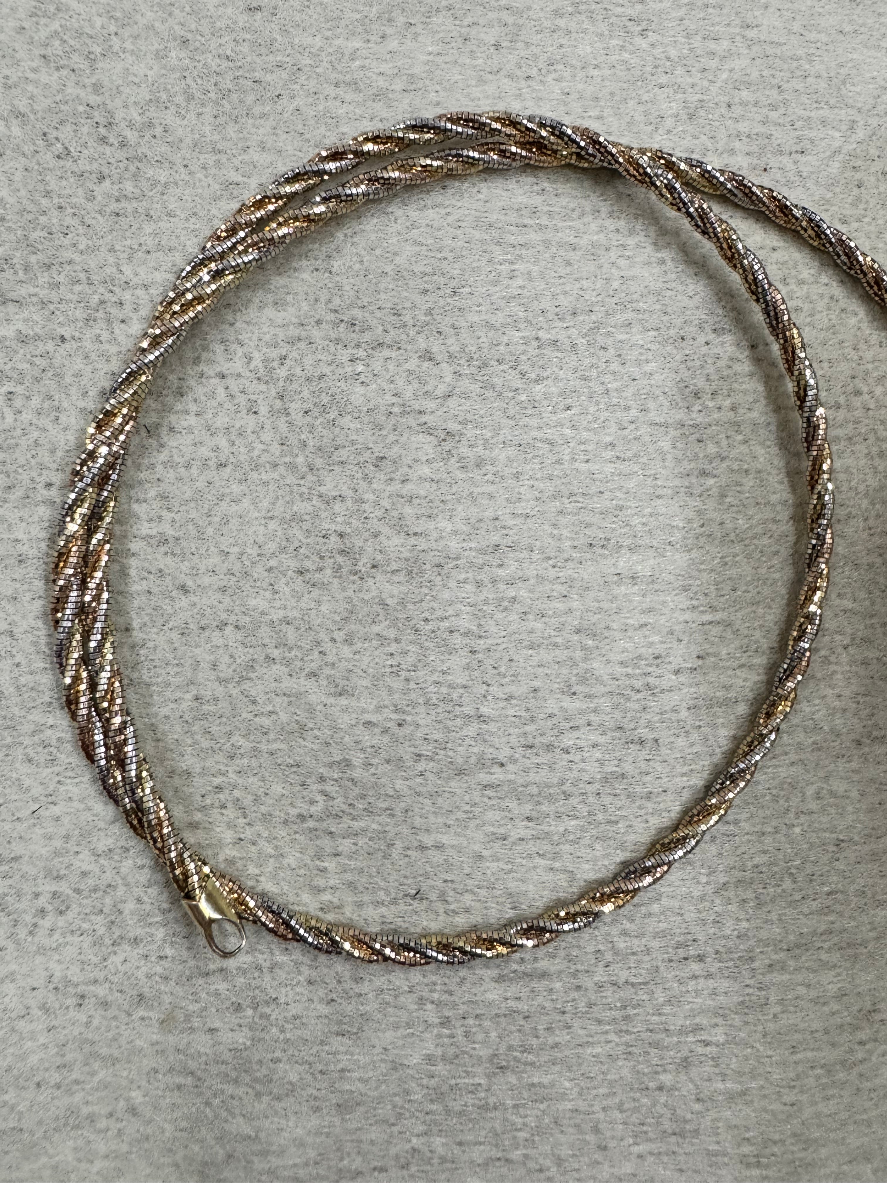 The sterling silver rope chain necklace on grey felt, showing the spiral of silver, gold-tone and rose-tone strands.