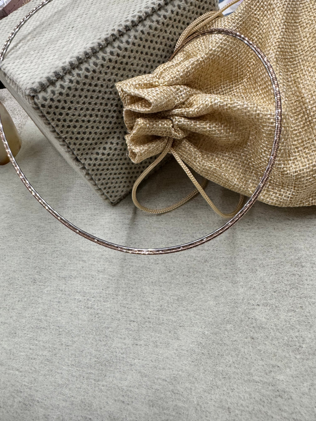 The 45 cm sterling silver snake chain necklace laid beside a jute drawstring pouch and folded fabric.