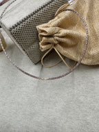 The 45 cm sterling silver snake chain necklace laid beside a jute drawstring pouch and folded fabric.