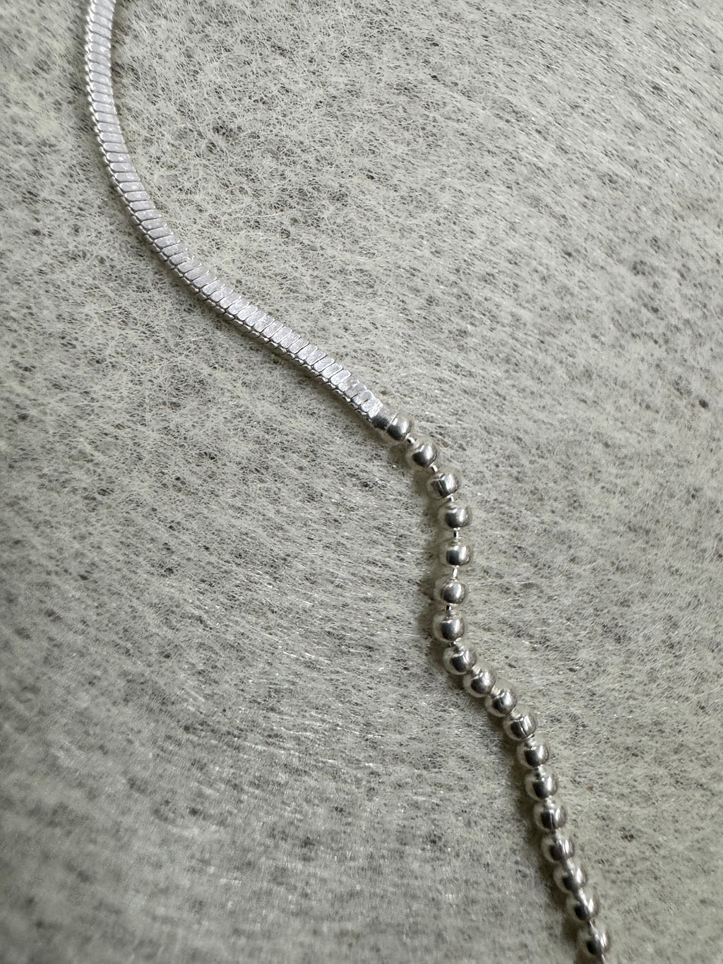 Macro view of the join between the snake chain and the bead section on the sterling silver necklace.