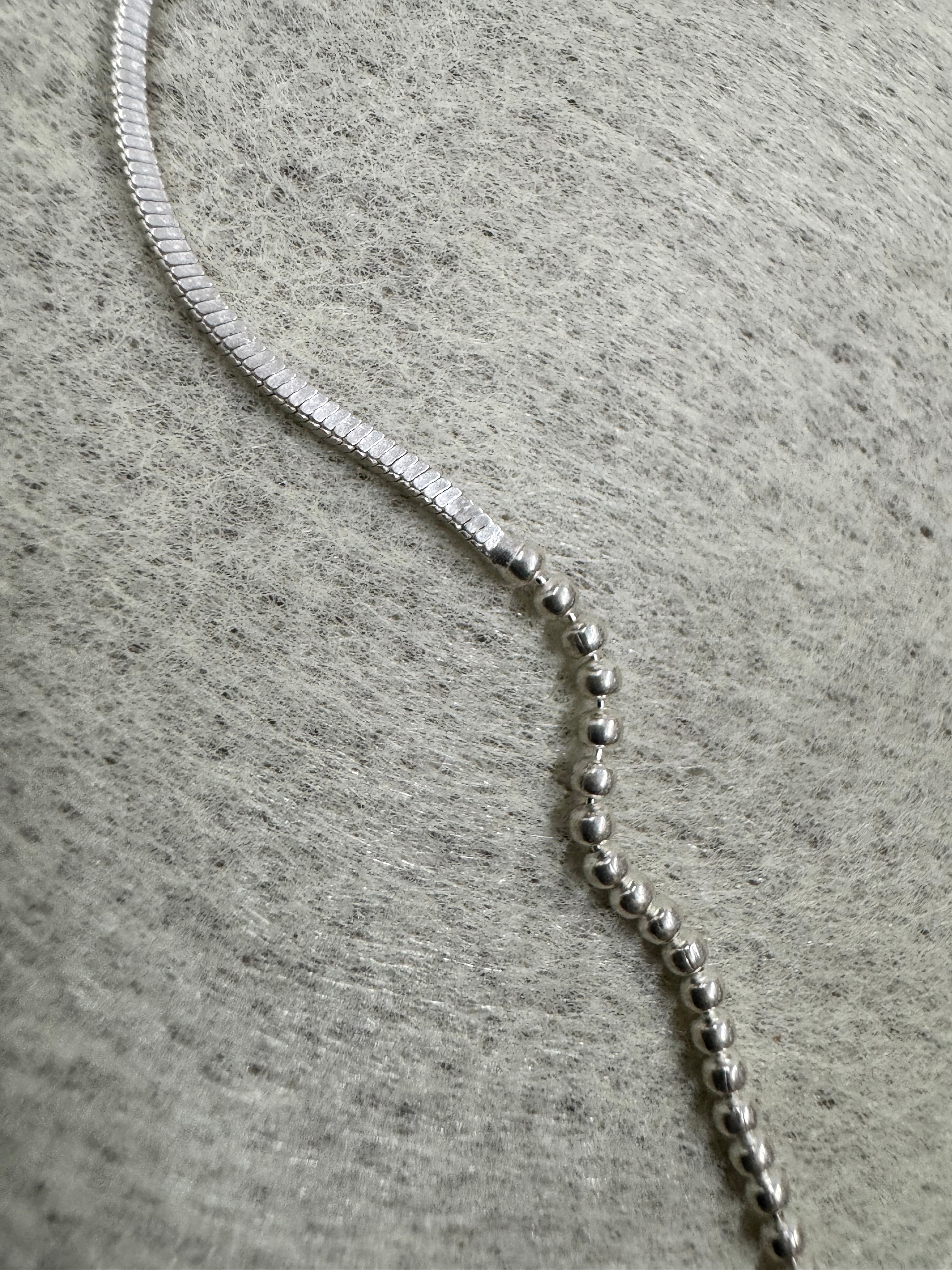 Macro view of the join between the snake chain and the bead section on the sterling silver necklace.