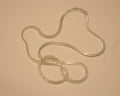 Sterling silver foxtail chain coiled loosely on a pale surface.