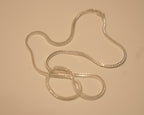 Sterling silver foxtail chain coiled loosely on a pale surface.