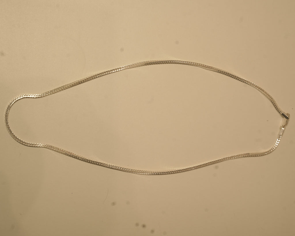 The silver foxtail chain laid out in a long oval to show how it falls.