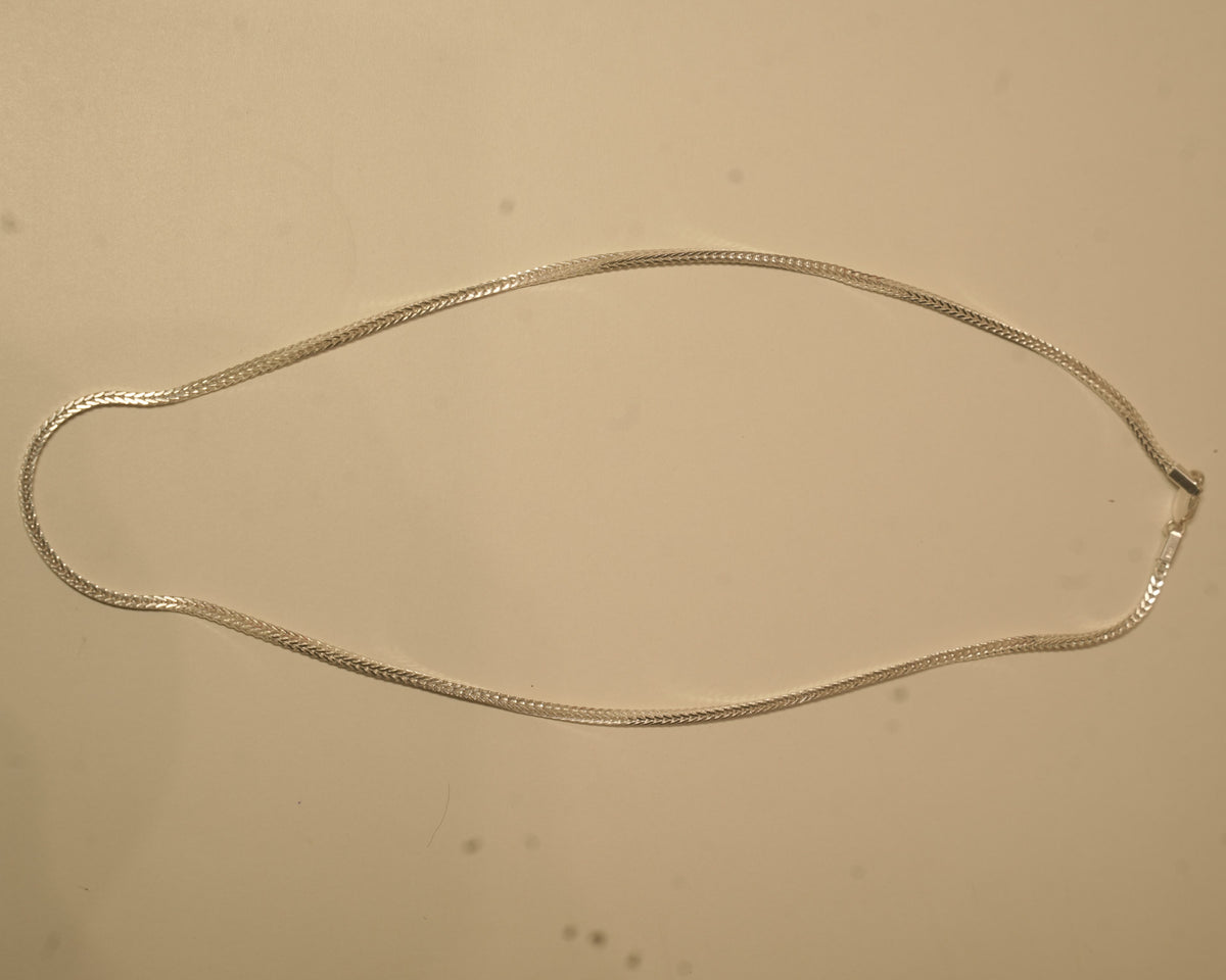 The silver foxtail chain laid out in a long oval to show how it falls.