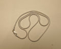 Sterling silver round snake chain coiled on a pale surface with the clasp to one side.