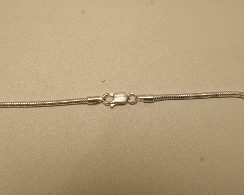 Close view of the lobster clasp on the silver snake chain, with the silver mark beside it.