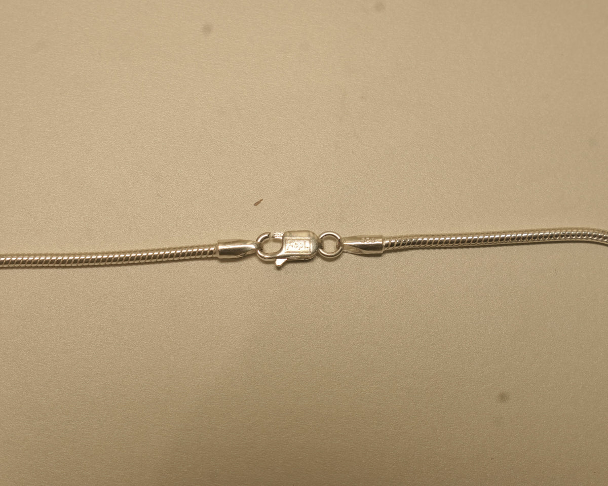 Close view of the lobster clasp on the silver snake chain, with the silver mark beside it.