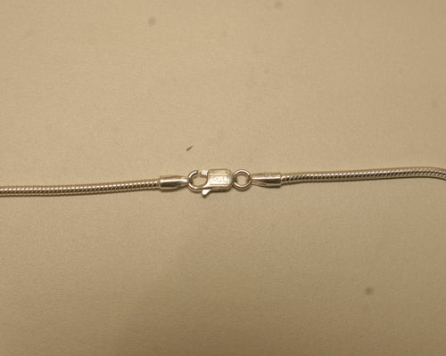 Close view of the lobster clasp on the silver snake chain, with the silver mark beside it.