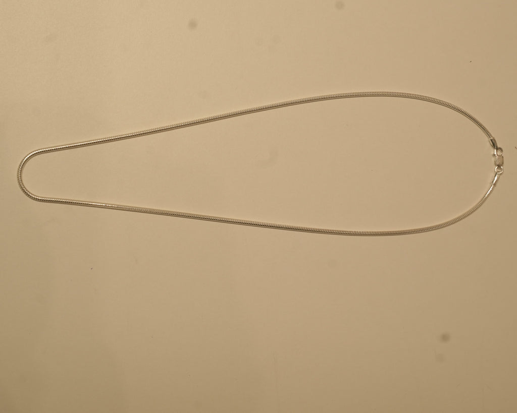 The silver snake chain laid out in a long oval to show how it falls.