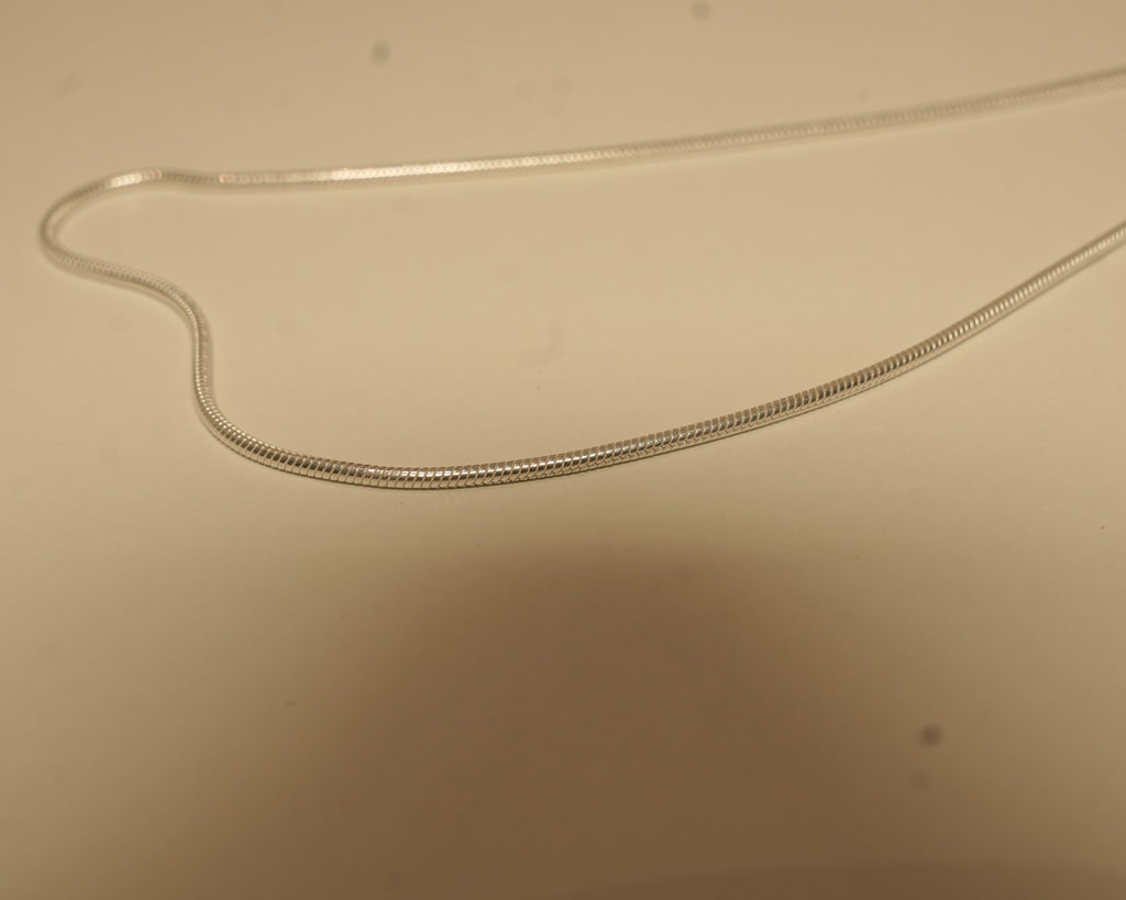 Close view of the silver snake chain, showing the smooth round surface with no visible links.