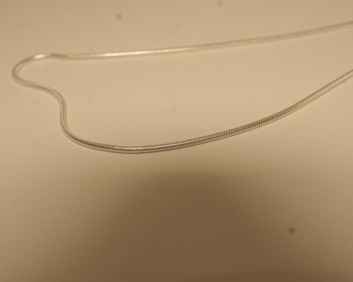 Close view of the silver snake chain, showing the smooth round surface with no visible links.