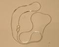 Sterling silver flat snake chain coiled on a pale surface with the S hook to one side.