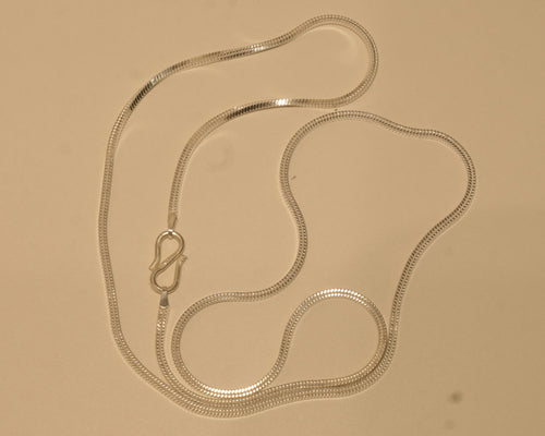 Sterling silver flat snake chain coiled on a pale surface with the S hook to one side.