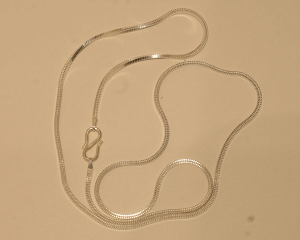 Sterling silver flat snake chain coiled on a pale surface with the S hook to one side.